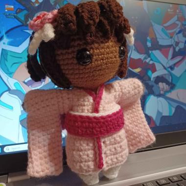 A little crocheted girl wearing a pink kimono